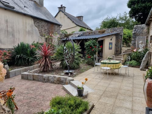 Cour intérieure du gîte Les Forges Du Lou à Jugon-les-Lacs avec plantes exotiques et espace détente
