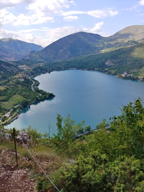 Alpine lake surrounded by green mountains and forested hills near Sulmona, Italy