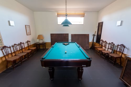 Sala de sinuca na pousada rural Casa das Jardas em Ladoeiro com mesa turquesa e cadeiras de madeira