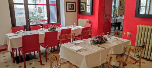 Stella CasaBono hotel dining room in Sulmona with red walls, white tablecloths, red chairs, and elegant table settings.