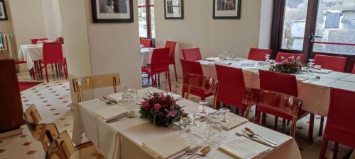 Elegant dining room at Stella CasaBono hotel in Sulmona with red chairs, white tablecloths, and floral centerpieces