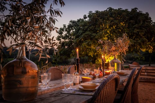 Saint Martin B&B outdoor dining setup at dusk in Ollioules with candlelit table, wine, and autumn trees