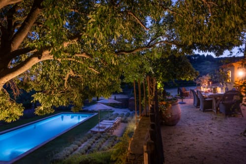 Twilight view of Saint Martin BnB in Ollioules with illuminated pool, terrace seating, and waterfront landscape