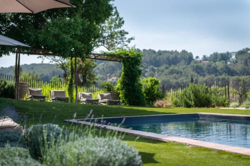 Luxury poolside patio at Saint Martin B&B in Ollioules with lavender, lounge chairs, vine-covered pergola, and vineyard