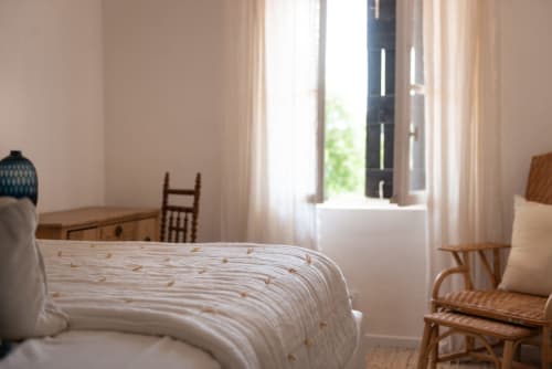 Bright bedroom at Saint Martin B&B in Ollioules with bed, rattan chair, and open doors to terrace