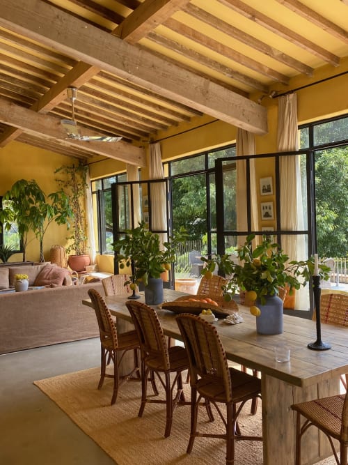 Salle à manger du Saint Martin BnB avec poutres en bois, murs jaunes, chaises en rotin et vue sur le jardin à Ollioules, France
