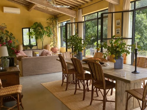 Le salon du Saint Martin BnB à Ollioules : murs jaunes, fauteuils en rotin, canapé, plantes et portes vitrées donnant sur le jardin