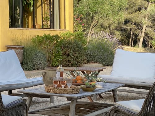 Outdoor lounge seating at Saint Martin B&B in Ollioules with wood furniture, white cushions, and Mediterranean-style garden