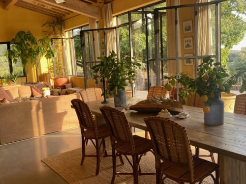Bright dining area at Saint Martin B&B Ollioules with woven chairs, potted plants, and panoramic glass doors overlooking lush