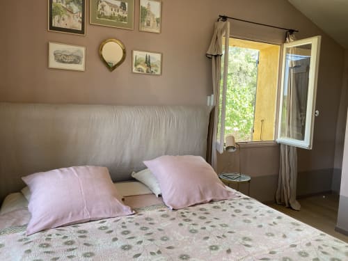 Bright bedroom at Saint Martin B&B in Ollioules with pink pillows, patterned bedding, and French doors opening to garden