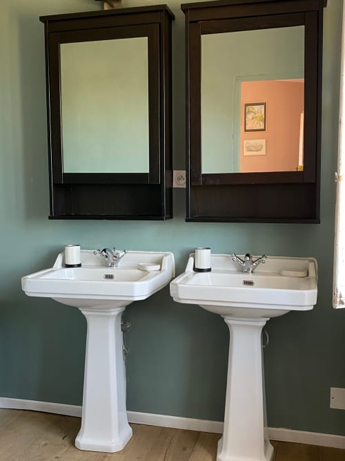 Dual pedestal sinks with dark mirrors in green bathroom at Saint Martin B&B in Ollioules