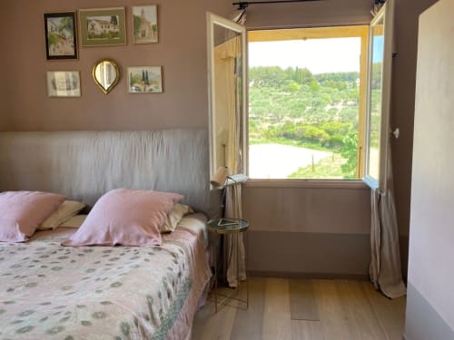 Bedroom at Saint Martin B&B in Ollioules with pink bedding, framed artwork, and open doors overlooking lush green landscape