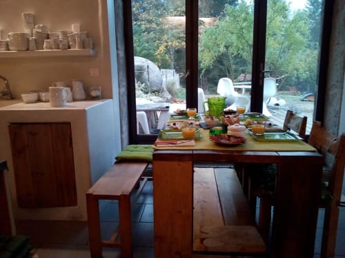 Furanelle B&B dining room in Saint Etienne with wooden table, green cushions, and garden view through large windows