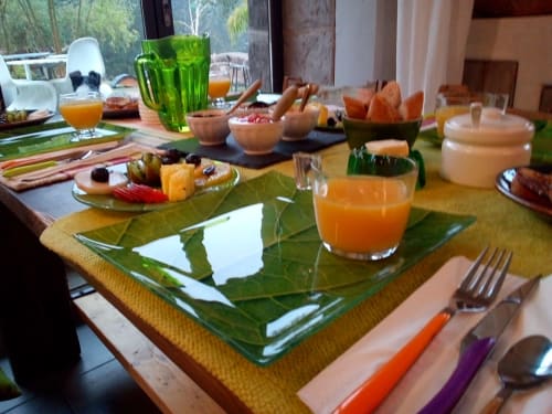 Elegant breakfast spread at Furanelle B&B Saint Étienne with fresh fruit, juice, and place settings on leaf-patterned plates