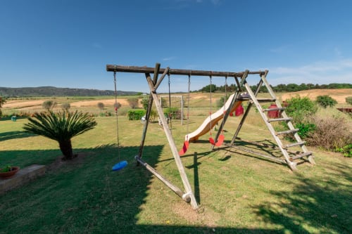 Parque infantil rústico de madeira com balanços e escorregador na propriedade rural Casa das Jardas em Ladoeiro, Portugal
