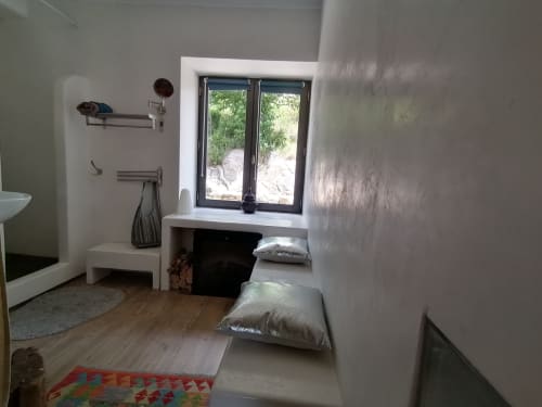 Minimalist bedroom at Furanelle B&B in Saint Etienne with grey walls, window view, cushions, and wooden floor