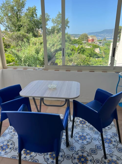 Sedie blu e tavolo sulla terrazza di Palazzo Porta con vista su Procida, mare e montagne