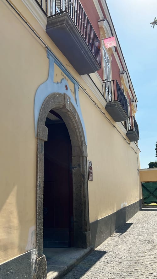 Ingresso del Palazzo Porta a Procida con portale arcato, insegna blu, balconate e vista sul mare