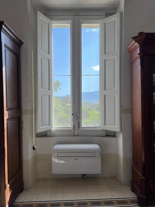 Luminosa alcova dell'appartamento a Palazzo Porta, Procida, con doppie porte bianche affacciate sulla vista mare e montagne