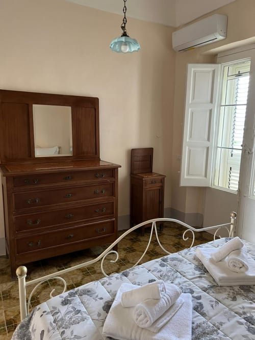 Accogliente camera da letto a Palazzo Porta, Procida con letto in metallo bianco, cassettone in legno e accesso alla vista mare