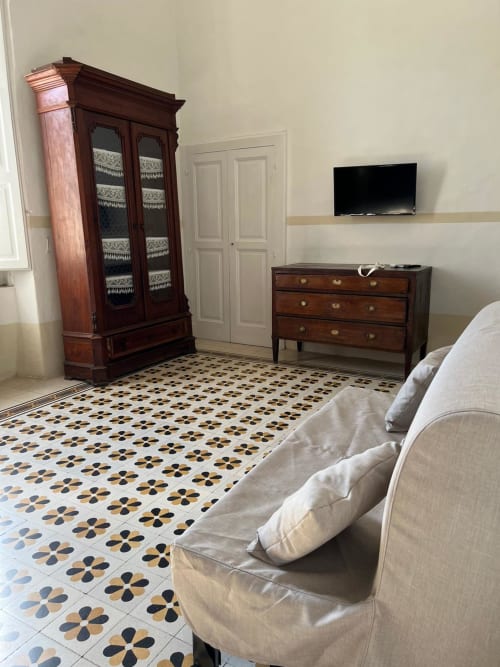 Camera elegante a Palazzo Porta, Procida con mobili in legno, piastrelle decorative, TV con vista mare e sedute color crema