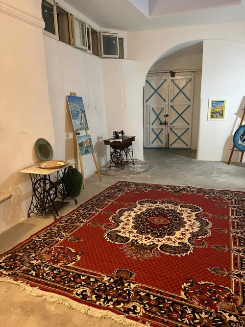 Appartamento Palazzo Porta a Procida con tappeto rosso ornamentale, tavolo con macchina da cucire e arco architettonico