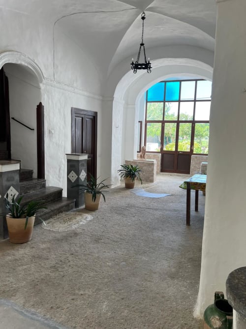 Corridoio dell'appartamento Palazzo Porta con archi bianchi, porte in legno, piante in vaso e vista sul giardino attraverso le grandi finestre