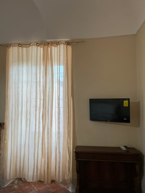 Camera presso Palazzo Porta a Procida con tende a righe, TV a parete e mobili in legno scuro