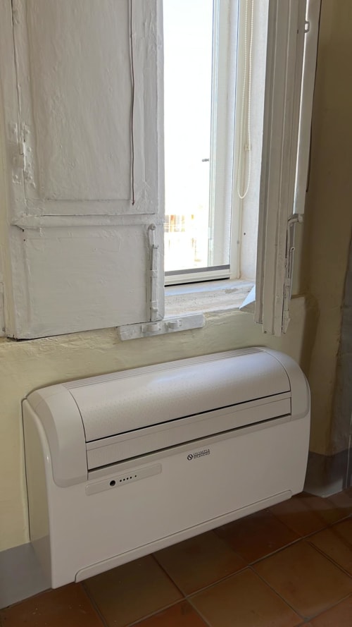 Unità di climatizzazione portatile nell'appartamento Palazzo Porta a Procida con accesso al balcone vista mare visibile sullo sfondo