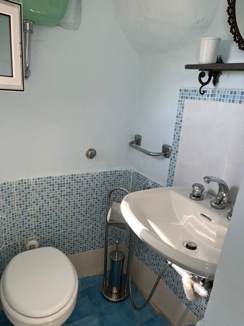 Moderno bagno a Palazzo Porta a Procida con piastrelle a mosaico blu, lavabo bianco e wc