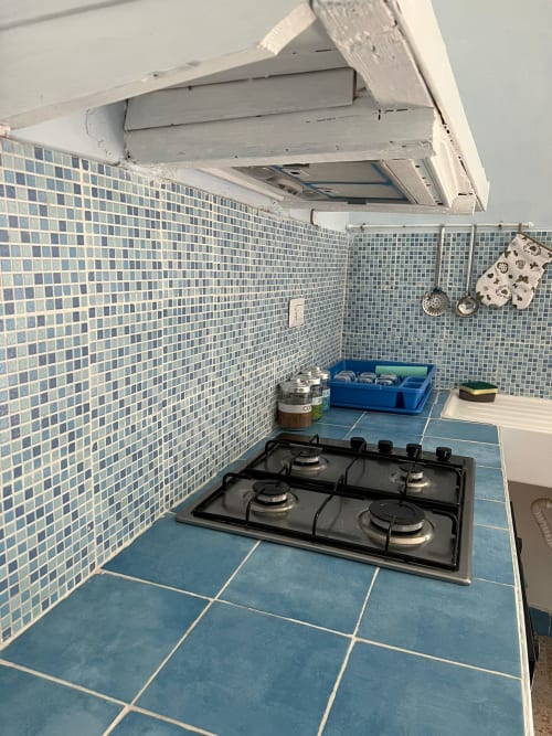 Cucina compatta a Palazzo Porta Procida con pavimenti in piastrelle blu, rivestimento a mosaico, fornello a gas e mobili bianchi