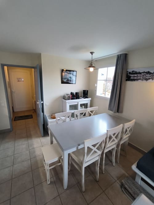 Salle à manger moderne avec table et chaises blanches, kitchenette et vue mer à Loc'Maria Belle Île en Mer