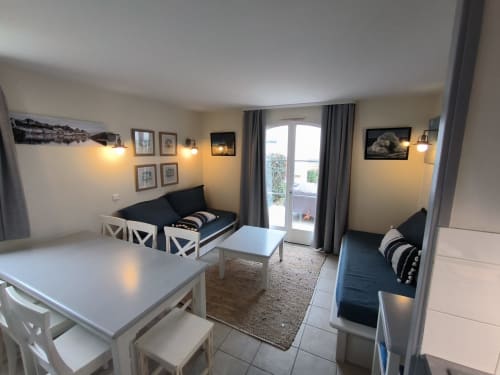 Séjour moderne avec table à manger, canapés noirs, portes avec vue mer et ambiance chaleureuse à Locmaria, Belle Île en Mer