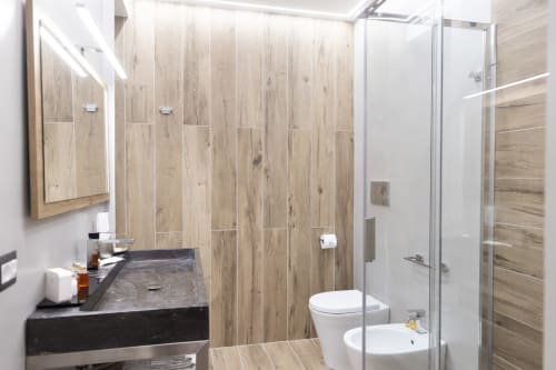 Bagno moderno nella camera Sovereign Herb del B&B I MORI Catania con piastrelle effetto legno, lavabo nero, WC e doccia in vetro