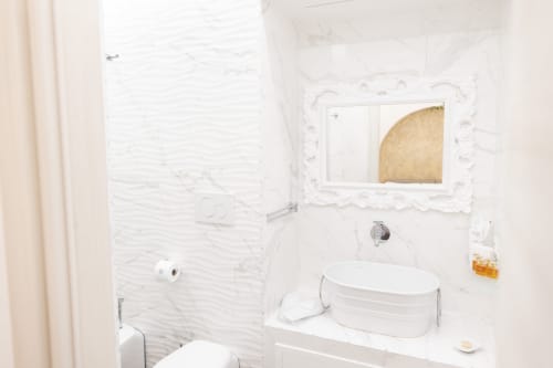 Banheiro moderno e luminoso da B&B I MORI Catania com azulejos de mármore branco, pia oval e espelho decorativo