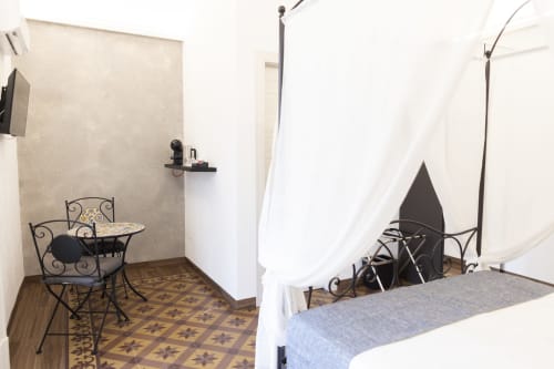 Camera moderna al B&B I MORI Catania con decori in ferro battuto, letto matrimoniale, zona living e tende bianche