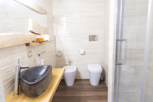 Baño moderno en la habitación Basileus del B&B I MORI Catania con lavabo de piedra oscura, detalles en madera y accesorios blancos