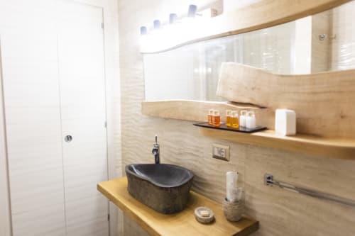 Baño moderno en la habitación Basileus del B&B I MORI Catania con lavabo de piedra oscura, tocador de madera, espejo y amenidades