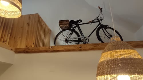 Bicicleta preta com cesto de vime exposta em prateleira de madeira no quarto da Pousada Kindnessmoon em Óbidos, Portugal