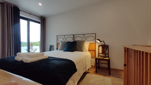 Quarto moderno na Kindnessmoon em Óbidos com vistas da cidade, cama de casal, portas de sacada e detalhes em madeira