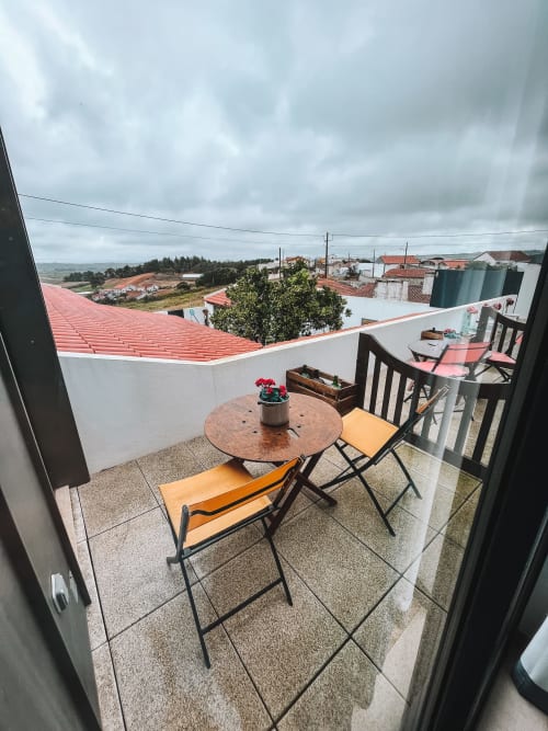 Varanda no telhado com cadeiras laranja e mesa redonda com vista para a vila de Óbidos, Portugal, na Kindnessmoon B&B