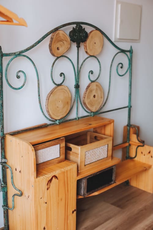 Cama com cabeceira de ferro forjado verde e decorações de fatias de madeira no quarto da pousada Kindnessmoon, Óbidos Portugal