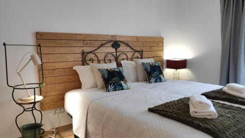 Quarto aconchegante na Kindnessmoon em Óbidos com cabeceira em madeira, roupa de cama branca, almofadas decorativas e luminária de cabeceira