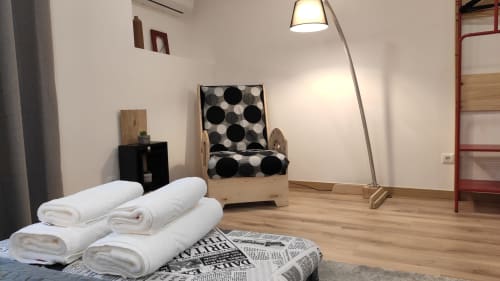 Quarto aconchegante em Kindnessmoon Alojamentos em Óbidos com toalhas enroladas brancas, móveis de madeira e cadeira estampada