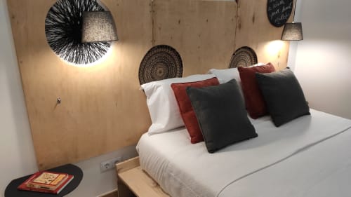 Quarto moderno do hotel com cama branca, almofadas decorativas, luminárias pendentes e arte em madeira na parede na Kindnessmoon em Óbidos,