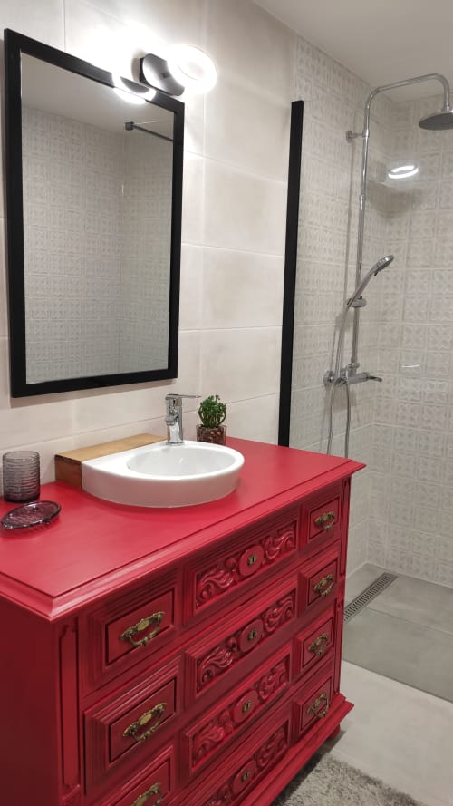 Casa de banho moderna com penteadeira vermelha ornamentada, lavatório redondo branco, espelho com moldura preta e duche de entrada aberta na Kindnessmoon em Óbidos