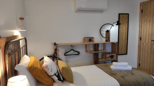 Quarto moderno na Kindnessmoon Óbidos com cama de madeira, almofadas amarelas, escrivaninha, decoração de bicicleta e ar-condicionado