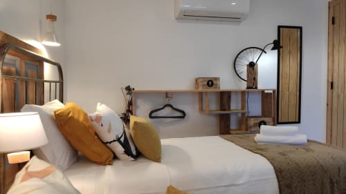 Quarto moderno na Kindnessmoon em Óbidos com cama branca, almofadas amarelas, prateleiras de madeira e vista para o jardim