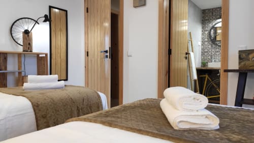 Quarto moderno na Kindnessmoon em Óbidos com camas geminadas, portas de madeira, toalhas brancas e decoração contemporânea