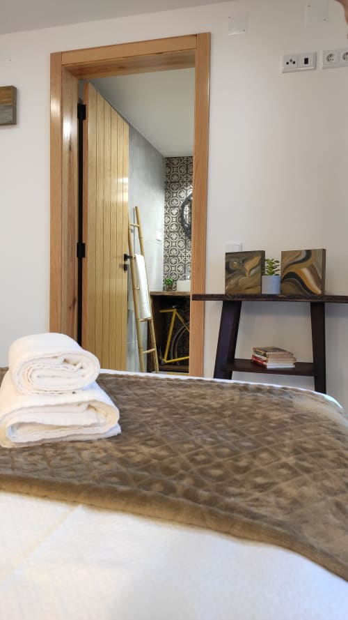 Quarto aconchegante no Kindnessmoon B&B em Óbidos com toalhas dobradas na cama, espelho com moldura de madeira e prateleira preta decorativa